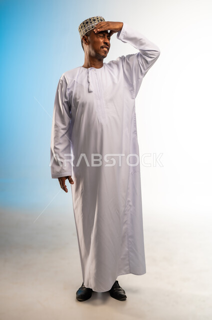Feeling tired and losing focus, feeling migraine, stress and pressure, portrait of an Arab Gulf Omani man wearing a dishdasha and a sleeve, putting his hands on his head and closing his eyes with gestures of severe headache, full-length body image, colored background
