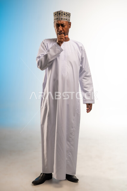 Symptoms of Coronavirus (COVID-19), need to seek help and go to the doctor, catching a cold, portrait of an Arab Gulf Omani man wearing a dishdasha and a sleeve, putting his hand on his mouth with coughing and pain gestures, feeling sick, tired and exhausted, full-length body image, colored background