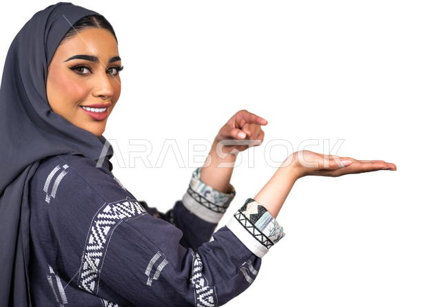 Portrait of a smiling Saudi Arabian Gulf woman looking at the camera, making various hand gestures, pointing her index finger on the other hand, holding