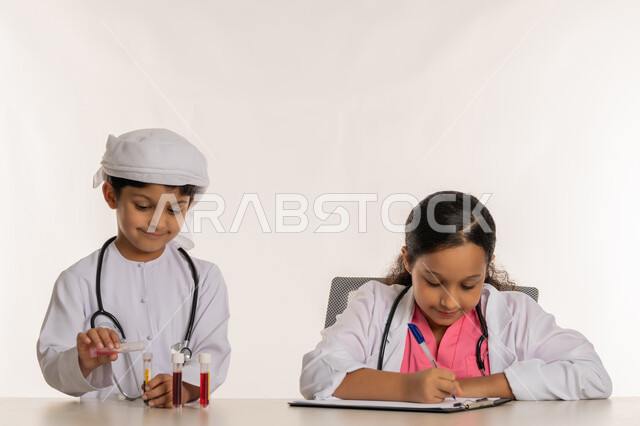 اجراء تجارب وتفاعلات حيويه في المختبر، تحديد واختيار المهنة المستقبلية منذ الصغر، بورتريه لفتاة عربية خليجية اماراتية ترتدي المعطف الأبيض تقوم بتدوين وكتابة النتائج ، ولد عربي خليجي اماراتي يرتدي الكندورة والعمامة يستخدم انابيب الاختبار،  خلفية بيضاء