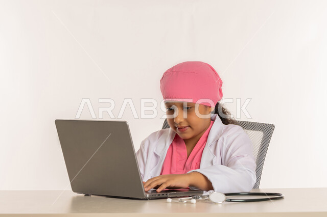 تحديد مهنة المستقبل، الأهداف والطموحات المستقبلية بالعمل في العيادات والمشافي، بورتريه لبنت عربية خليجية اماراتية ترتدي المعطف الأبيض تدون نتائج الفحوصات بالسجل الطبي، فتاة سعودية تجلس امام الطاولة تقوم بإعداد التقارير الطبيه على الحاسوب المحمول، خلفية بيضاء