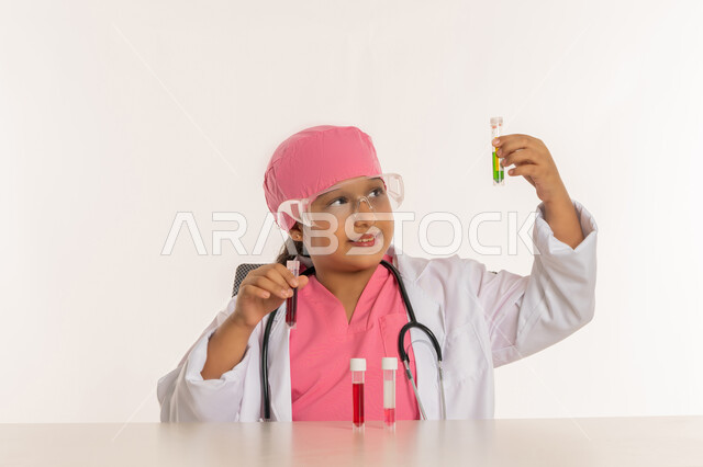 اختيار المهنة المستقبلية منذ الصغر، أمنية الحصول على مهنة الباحثة الكيميائية، اجراء تجارب وتفاعلات حيويه في المختبر، بورتريه لفتاة عربية خليجية اماراتية ترتدي المعطف الأبيض ونظارات حماية وتستخدم انابيب الاختبار، بنت سعودية تقوم بأبحاث علمية، خلفية بيضاء