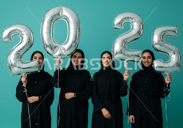 Celebrating New Year's Eve 2025, Joy of the New Year, Gestures of Happiness and Joy, Optimism and Welcome to the New Year, Portrait of Veiled Saudi Arabian Gulf Women Wearing Black Abayas Holding Large Silver Balloons in Their Hands, Blue Background