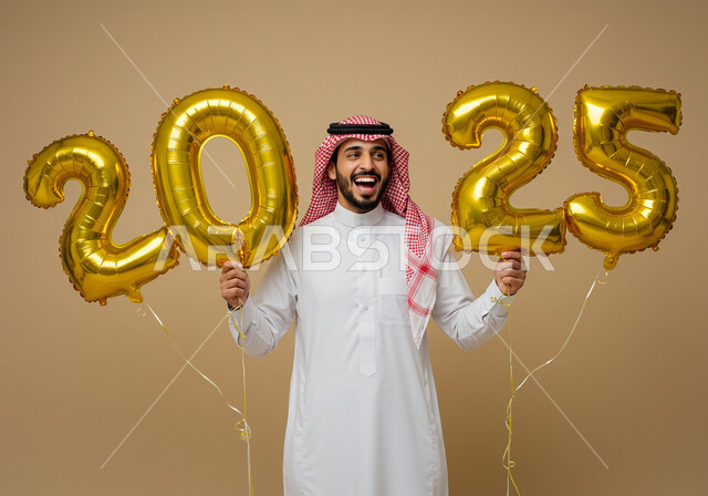 الاحتفال بعيد رأس السنة الميلادية 2025, الاستعداد لاستقبال العام الجديد, إيماءات السعادة والسرور, التفاؤل والترحيب بالسنة الجديدة, بورتريه لرجل عربي خليجي سعودي مبتسم يرتدي الثوب التقليدي والشماغ يحمل بيديه بالونات ذهبية كبيرة, خلفية بيج