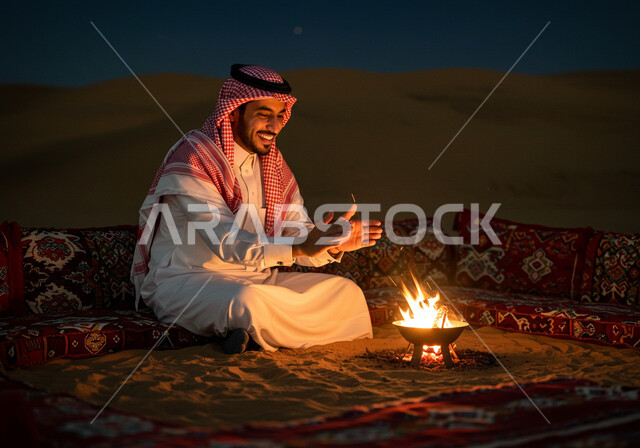 الرمال الذهبية الناعمة, رحلة تخييم سياحية ممتعة وسط الصحراء، الجو الليلي الهادئ, التشكيلات والكثبان الرملية, كشتة و جلسة بر شبابية, مخيم سياحي في منطقة صحراوية, رجل عربي خليجي سعودي يرتدي الثوب التقليدي والشماغ يجلس أمام شعلة الحطب