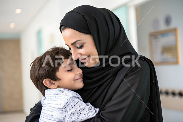 قضاء أوقات ممتعة باللعب مع الأولاد، إيماءات السعادة والأمان، حنان الأمهات ورعايتهم للأبناء، صورة مقربة لأم عربية خليجية سعودية ترتدي الحجاب والعباءة السوداء تحتضن ابنها، الملامح الناعمة والبريئة، مفهوم الاناقة والاهتمام بالمظهر الخارحي