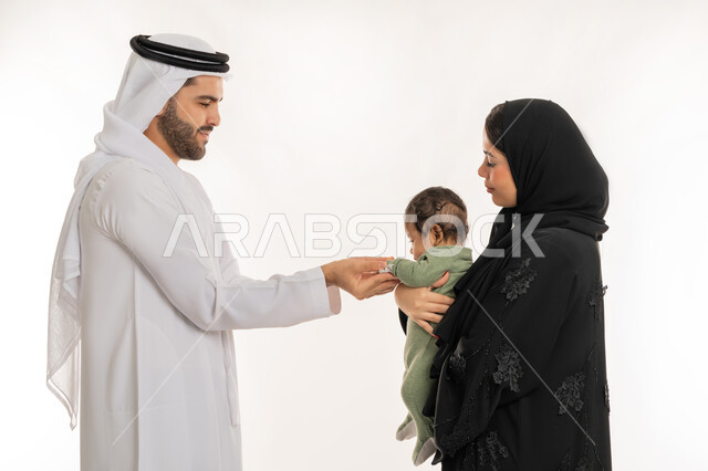 قضاء وقت ممتع مع الطفل, بورتريه مقرب من الجانب لعائلة عربية خليجية إماراتية مع ابنهم الرضيع, مفهوم الاسرة السعيدة, ملاعبة الأبناء بعطف واهتمام، إيماءات الحب والحنان على الصغار, تحمل المسؤولية والعناية بالأطفال، خلفية بيضاء