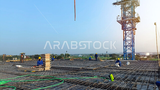 Implementation of the construction plan and the formation of the metal structure, a building under construction and construction in the Kingdom of Saudi Arabia, the concept of structural and architectural engineering, heavy equipment, cranes and high scaffolding, construction works, pouring concrete and laying the initial foundations