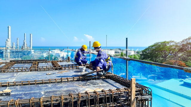 صب الخرسانات ووضع الأساسات المعدنية, مفهوم الهندسة الانشائية والمعمارية، تنفيذ مخطط الإعمار وتشكيل الهيكل المعدني, عاملان عربيان خليجيان سعوديان يرتديان سترة وخوذة الحماية يقومان بأعمال البناء على السطح