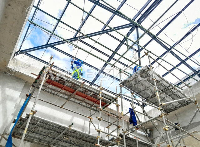 بناء هيكل السقف المعدني, مبنى قيد الإنشاء والتشييد, صب الخرسانات ووضع الأساسات المعدنية, مفهوم الهندسة الانشائية والمعمارية, عمال عربيين خليجيين سعوديين يرتدون سترة وخوذة الحماية يقومون بأعمال البناء