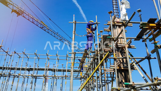 High scaffolding construction, concept of structural and architectural engineering, pouring concrete and laying initial foundations, implementing the construction plan and forming the metal structure, a Saudi Arabian Gulf worker doing construction work