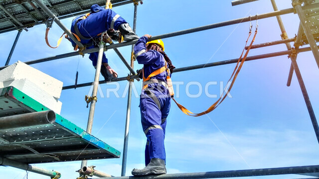 Steel structure construction, building under construction, concrete pouring and foundation laying, structural and architectural engineering concept, two Saudi Arabian Gulf workers wearing protective jacket and helmet doing construction work