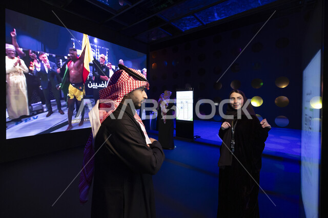 تطوير صناعة المحتوى، ملتقى عالمي لتبادل الخبرات وعقد الشراكات، مؤتمرات وفعاليات ثقافية مشهورة، رجل عربي خليجي سعودي يرتدي الثوب التقليدي والشماغ يقف مع امراة في منصة صناع التاثير في الرياض، تعزيز دور المملكة العربية السعودية في مجال الإعلام الرقمي