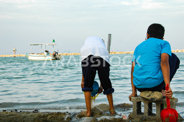 Summer fun cruise, having fun, enjoying summer vacation, coastal tourist places in Saudi Arabia, Saudi Arabian Gulf boys in casual clothes playing on the sword of Dammam city