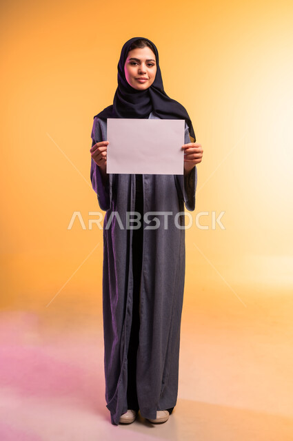 Blank white mockup, advertisements and marketing offers, using illustrations and educational tools, portrait of a veiled Saudi Arabian Gulf woman wearing an abaya holding a blank white paper in her hand, full length body, colored background