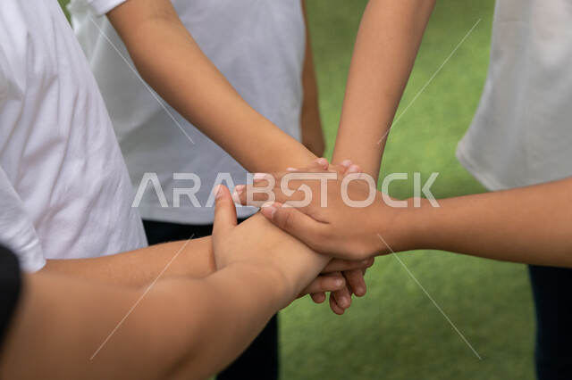 تعزيز العلاقات الاجتماعية بين الطلاب في المدرسة, العمل الجماعي وتبادل الدعم بين الاصدقاء, مفهوم تحقيق الأهداف المشتركة, صورة مقربة لمجموعه من الأيادي الموضوعه فوق بعضها في إحدى مدارس الامارات العربية المتحدة, المساهمة في تطوير جيل واع ومؤثر