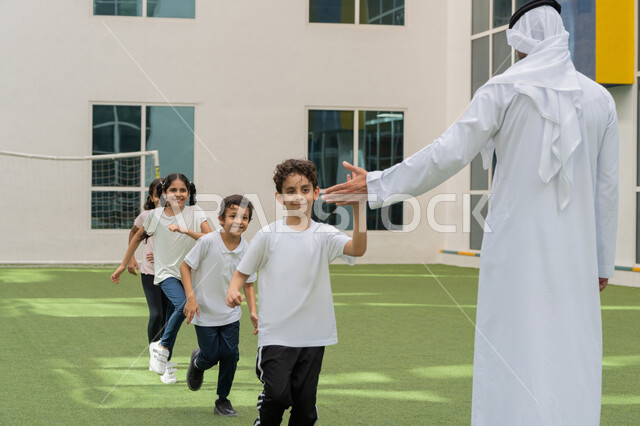 الاستمتاع في قضاء وقت الفراغ مع الاصدقاء، الاستعداد و الاحماء لممارسة التمرين الرياضي برفقة المدرب, نشاط ترفيهي للأطفال, مجموعه من الطلاب العربيين الخليجيين الاماراتيين يقومون باللعب في باحة المدرسة في الامارات العربيه المتحدة, تعليم أساسيات الرياضة