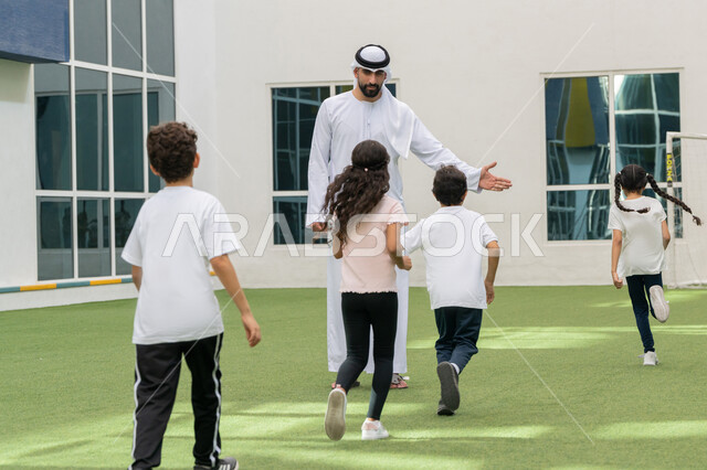 الاستعداد و الاحماء لممارسة التمرين الرياضي برفقة المدرب, نشاط ترفيهي للأطفال, مجموعه من الطلاب العربيين الخليجيين الاماراتيين يقومون باللعب في باحة المدرسة في الامارات العربيه المتحدة, تعليم أساسيات الرياضة, الاستمتاع في قضاء وقت الفراغ مع الاصدقاء
