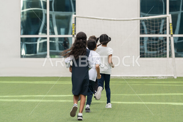 فعالية ونشاط ترفيهي للأولاد في مدارس الامارات العربية المتحدة, أجواء مليئة بالمرح والتفاعل الإيجابي, صورة من الخلف لمجموعه من الطلاب العربيين الخليجيين الاماراتيين يقومون بممارسة رياضة الجري في الهواء الطلق في باحة المدرسة