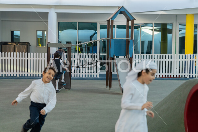 الجري واللعب والمرح مع الأصدقاء، ايماءات السعادة والفرح والسرور، طلاب عرب خليجيين اماراتيين يركضون في باحة المدرسة أثناء الفسحة، قضاء وقت ممتع في النشاط الترفيهي في مدارس الإمارات العربية المتحدة