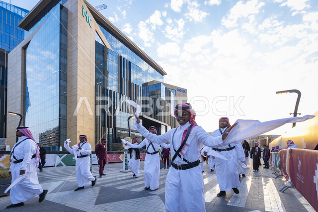 Visitors flock to attend the Camel Year Competition and Festival in Riyadh, popular Arab heritage activities, participation in events and festivals in the Kingdom of Saudi Arabia, an Arab Gulf Ardah band wearing traditional dress and shemagh performing folk dance, promoting cultural identity and consolidating Saudi heritage