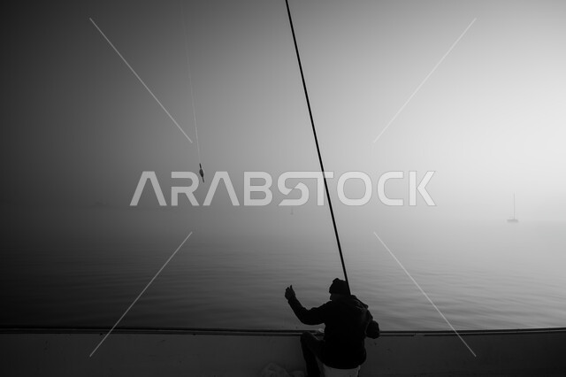 نشاط ترفيهي ممتع وسط الضباب, ممارسة هواية صيد السمك, رحلة وجولة صيفية ممتعة, الأماكن والمعالم السياحية الساحلية المشهورة, الواجهة البحرية لدولة قطر, صورة ظلية لصياد عربي خليجي قطري يمسك السنارة, سيلوليت