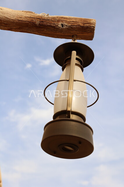 أداوت إنارة بدائية تراثية تقليدية، صورة مقربة لفانوس شعبي عربي سعودي اثري في النهار, الفوانيس المعدنية المعلقة على الاعمدة الخشبية في قرى المملكة العربية السعودية