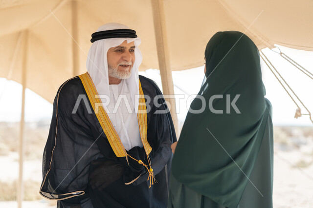 تأسيس الاتحاد 2 ديسمبر، صورة مقربة لرجل عربي خليجي إماراتي يرتدي الكندورة والغترة والبشت يقف مع إمراة ترتدي العباءة والحجاب داخل خيمة في الصحراء، ايماءات السعادة والسرور والاعتزاز، تبادل الاحاديث وزيارة الاماكن التاريخية القديمة، ذكرى اليوم الوطني الاماراتي 1971