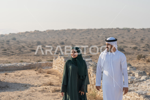 تأسيس الاتحاد 2 ديسمبر، شاب عربي خليجي إماراتي يرتدي الكندورة والغترة يتجول مع إمراة ترتدي العباءة والحجاب في منطقة أثرية في الصحراء، تعابير وايماءات الفخر والاعتزاز وحب الوطن، تبادل الاحاديث وزيارة الاماكن التاريخية القديمة، اليوم الوطني الاماراتي 1971