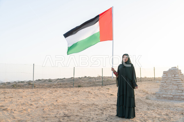 UAE National Day 1971 Remembrance, Union Founding Anniversary December 2, Emirati Gulf Arab Woman Wearing Hijab and Abaya Holding UAE Flag in Hand Standing in Archaeological Area in Desert, Flag Day November 3, Love and Pride of Homeland, Desert Nature Background