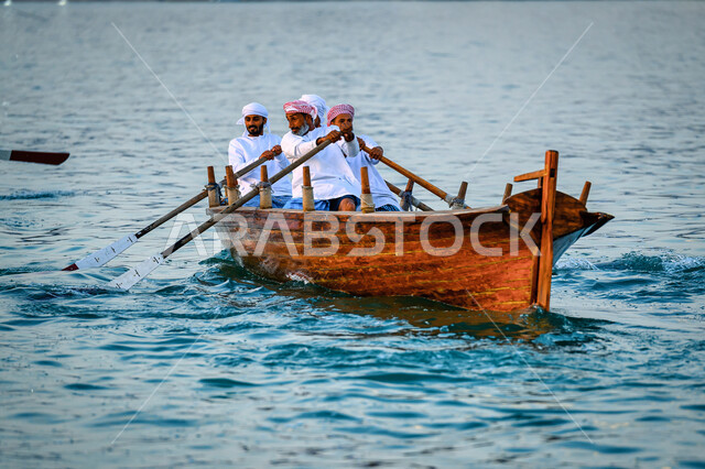 الاستمتاع بالرحلة البحرية, ممارسة هواية الصيد، رجال عرب خليجيون قطريون يرتدون الثوب التقليدي يبحرون في قارب خشبي على شاطئ مدينة الدوحة، مهرجان كتارا الرابع عشر للمحامل التقليدية, نشاط ترفيهي ممتع, فعاليات وأنشطة تراثية وثقافية