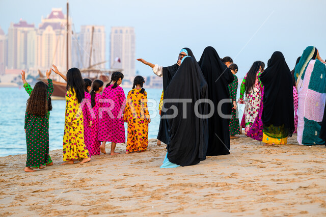 Cultural heritage events and activities, old Qatari customs and traditions, a group of Qatari Gulf Arab women wearing traditional costumes celebrating on the beach of Doha, celebrating the 14th Katara Traditional Dhow Festival