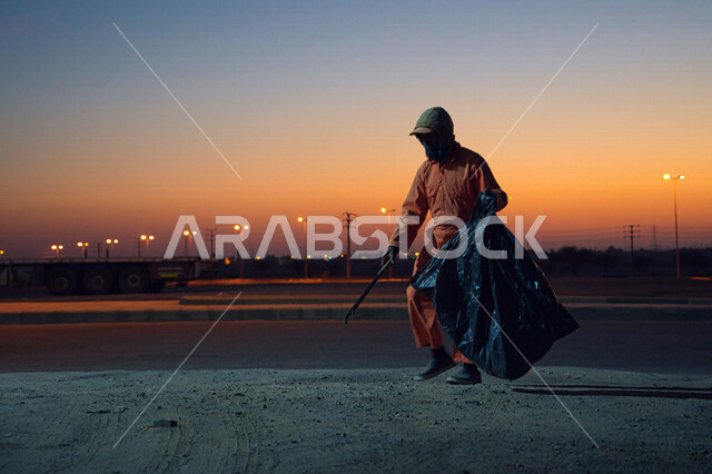 صورة لعامل النظافة يرتدي الزي الخاص بالعمل ، يهتم بنظافة شوارع المدينة في الصباح الباكر ، جمال المملكة العربية السعودية ، منظر شروق الشمس في الصباح الباكر