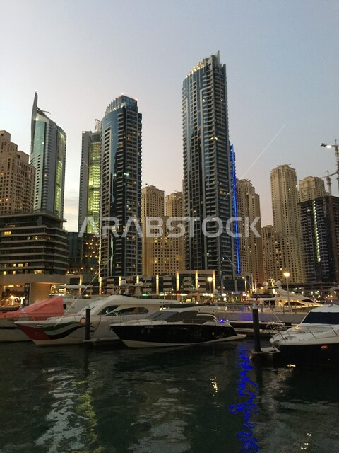 الفن الهندسي للأبراج وناطحات السحاب، مجموعة من السفن والقوارب المائية في الميناء في النهار، جذب السياح من أنحاء العالم، النقل البحري في مرسى دبي، التطور العمراني للمرافق التجارية والسكنية، مكان سياحي مشهور، الواجهة البحرية الساحلية في الإمارات العربية المتحدة