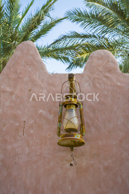 تصوير مقرب لمصباح اثري صدئ ، مصباح عربي تقليدي قديم معلق على الجدار ، الفانوس القديم على سياج من الطين