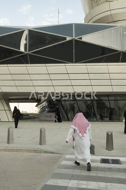 تيسير الحركه المروريه للشعب، تقدم وتطور وسائل النقل والمواصلات الحديثة في المملكة, التنقل السريع والآمن في السعوديه، الاستعداد لركوب القطار، صورة من الخلف لرجل عربي خليجي سعودي يرتدي الشماغ والثوب التقليدي يركض لمحطة المترو في مدينة الرياض