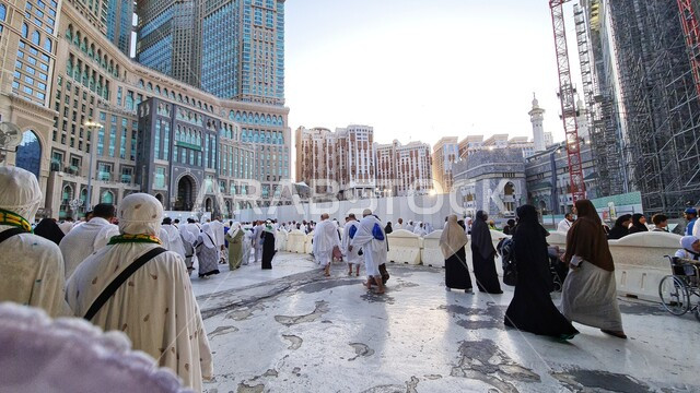 Pilgrims and Umrah performers gather in the courtyard of the Grand Mosque, Mecca, Saudi Arabia, performing Hajj and Umrah rituals, architectural art of the towers surrounding the Grand Mosque, sacred Islamic religious landmarks