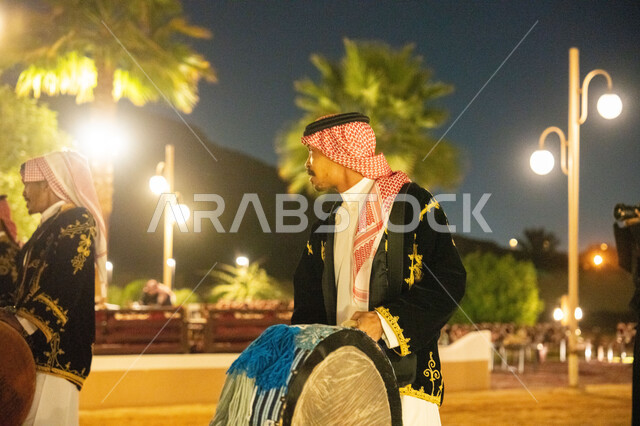 فعالية واحتفال شعبي ترفيهية، فرقة عرضة نجدية، مجموعة من الرجال العرب الخليجيين السعوديين يرتدون الثوب التقليدي والشماغ يقومون بالاحتفال وقرع الطبول، عرض فلكلور تراثي