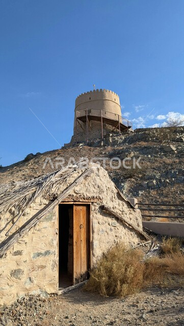 حصن تاريخي وكوخ تقليدي في حتا في إمارة دبي، الفن الهندسي المعماري على الطراز الحجري القديم، الطبيعة الصخرية والقمم والمرتفعات في المناطق الجبلية في النهار, منطقة أثرية سياحية مشهورة في الإمارات العربية المتحدة
