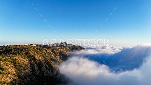 View of thick clouds and clouds on top of the mountain, highlands and plateaus in mountainous areas, natural landmarks and tourist places in the Kingdom of Saudi Arabia, peaks of the Al-Sawda Mountains in the Asir region during the day