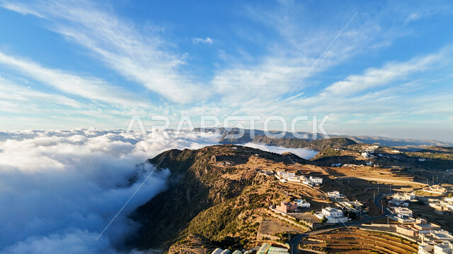 View of thick clouds and clouds on top of the mountain, highlands and plateaus in mountainous areas, natural landmarks and tourist places in the Kingdom of Saudi Arabia, peaks of the Al-Sawda Mountains in the Asir region during the day