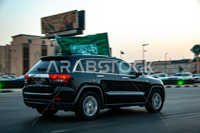 الاحتفال بالأعياد والمناسبات الوطنية, ذكرى اليوم الوطني السعودي 23 سبتمبر, الفخر والاعتزاز والانتماء للوطن, فعالية احتفالية ترفيهية, يوم العلم السعودي 11 مارس, سيارة جيب سوداء تسير في إحدى الشوارع وترفع علم المملكة العربية السعودية