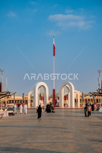 علم دولة قطر يرفرف في السماء, الأعياد والمناسبات الوطنية, الاحتفال باليوم الوطني القطري 18 ديسمبر, مفهوم الحب والانتماء للبلاد, مجموعة من الأشخاص عربيين خليجيين قطريين يتجولون في ساحة درب الساعي في مدينة الدوحة
