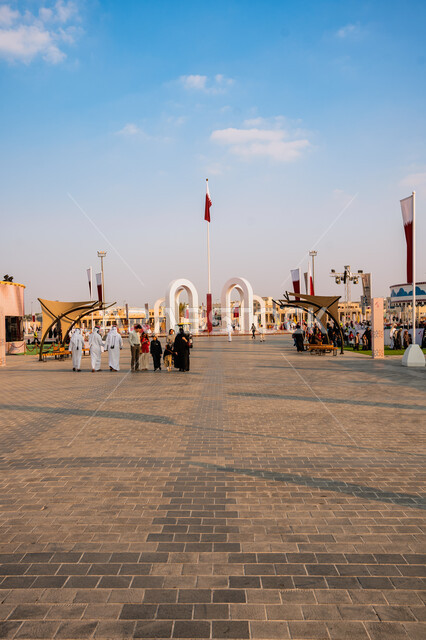 الأعياد والمناسبات الوطنية, الاحتفال باليوم الوطني القطري 18 ديسمبر, مفهوم الحب والانتماء للبلاد, مجموعة من الأشخاص عربيين خليجيين قطريين يتجولون في ساحة درب الساعي في مدينة الدوحة, علم دولة قطر يرفرف في السماء