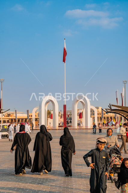 الاحتفال باليوم الوطني القطري 18 ديسمبر, مفهوم الحب والانتماء للبلاد, مجموعة من الأشخاص عربيين خليجيين قطريين يتجولون في ساحة درب الساعي في مدينة الدوحة, علم دولة قطر يرفرف في السماء, الأعياد والمناسبات الوطنية