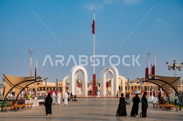 الأعياد والمناسبات الوطنية, الاحتفال باليوم الوطني القطري 18 ديسمبر, مفهوم الحب والانتماء للبلاد, مجموعة من الأشخاص عربيين خليجيين قطريين يتجولون في ساحة درب الساعي في مدينة الدوحة, علم دولة قطر يرفرف في السماء