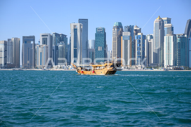 الفن الهندسي المعماري لبناء الأبراج وناطحات السحاب, قارب خشبي يبحر في مدينة الدوحة في النهار, المباني والمنشآت المطلة على البحر، الأماكن والمعالم السياحية المشهورة في قطر, جذب واستقطاب السياح من أنحاء العالم