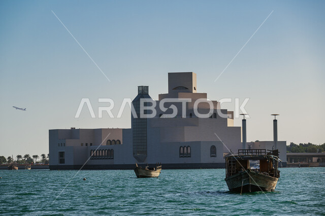 Museum of Islamic Art in Doha during the day, famous historical cultural tourist attractions, recreational cruise and sea tour areas, distinctive architectural design of museums in Qatar, wooden boat sailing in the middle of the sea