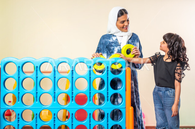 تنمية قدرات الأولاد العقلية عن طريق الألعاب الفكرية والحسية، اصطحاب الأبناء إلى صالات اللعب المخصصة للأطفال، قضاء اوقات ترفيهية ممتعة، فتاة عربية خليجية سعودية ترتدي الزي الكاجوال برفقة والدتها تلعبان سويا، القيام بنشاطات عائلية في عطلة نهاية الأسبوع