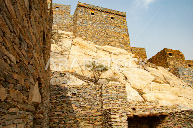 Ancient Arab architecture, rocky terrain, mountain peaks and heights, heritage stone buildings and houses, the ancient village of Dhi Ain in the city of Al Baha in the south of the Kingdom of Saudi Arabia, famous historical tourist attractions, natural places to attract and attract tourists